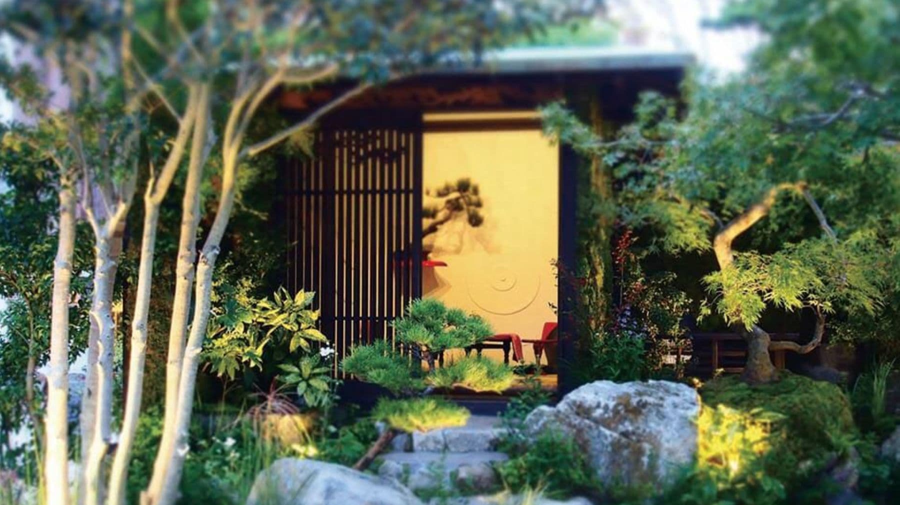 格子戸の建屋を、木々と石組みが囲む