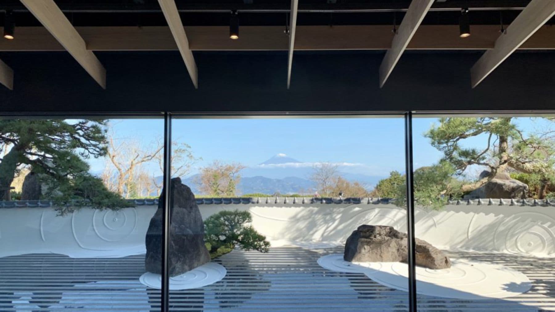 ガラス越しに見る白砂と石の坪庭。遠くに富士山