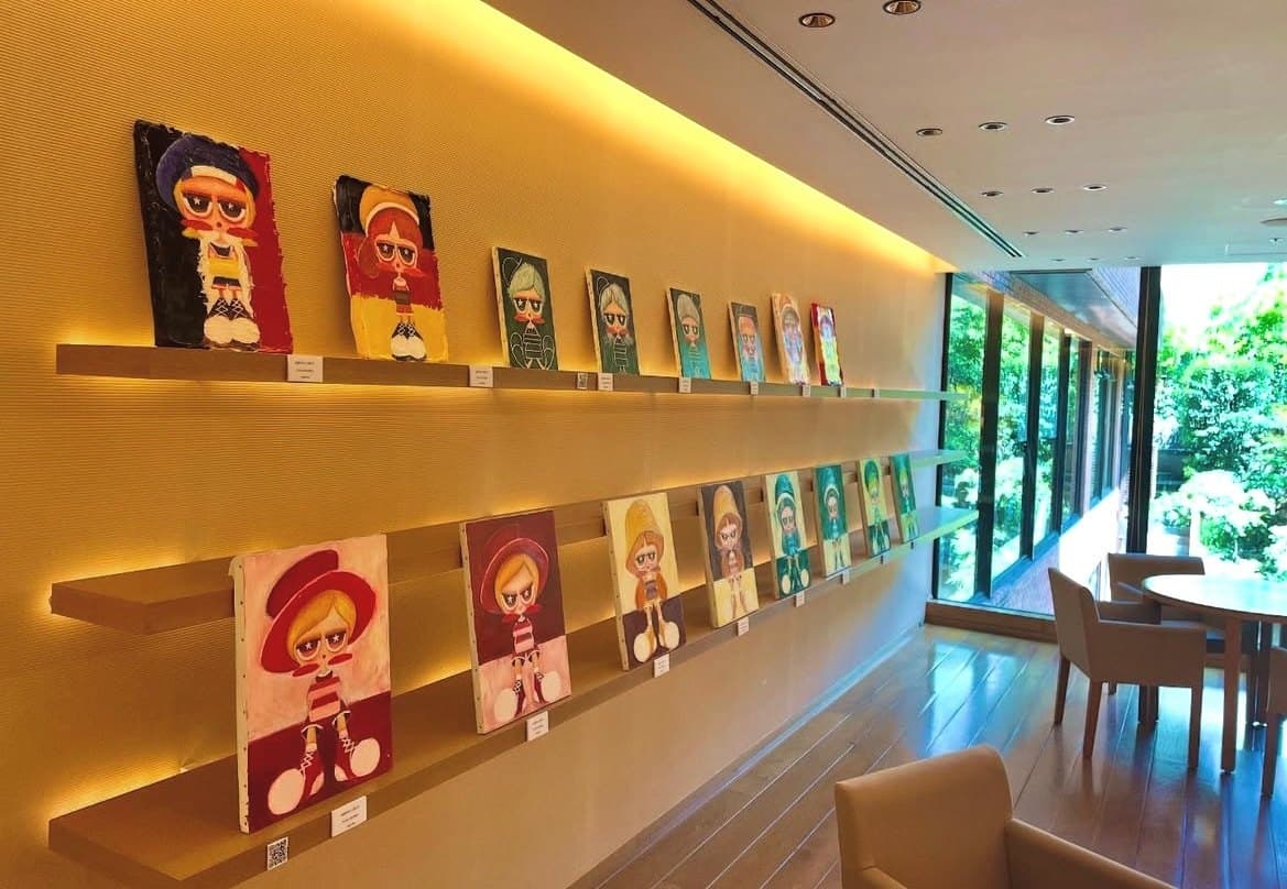 Персональная выставка в Hyatt Regency Kyoto. Работы расставлены в два яруса на полках вдоль стены у окна