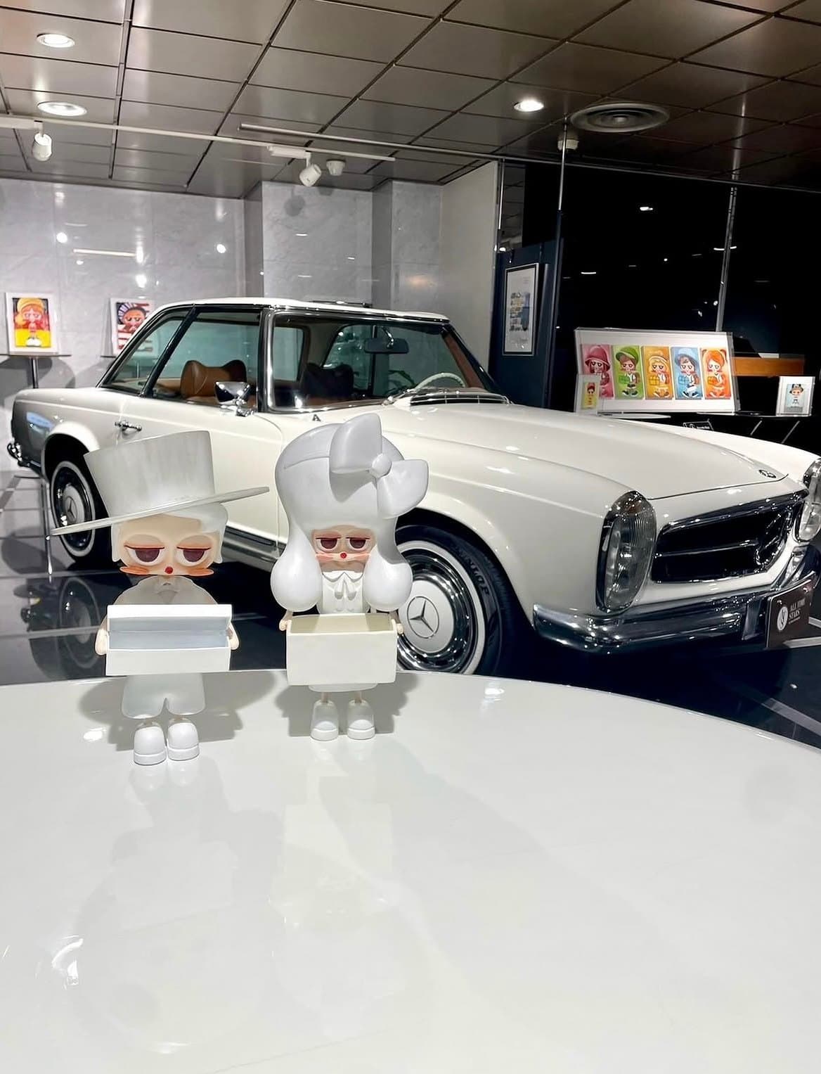 Œuvre en volume placée devant une voiture blanche