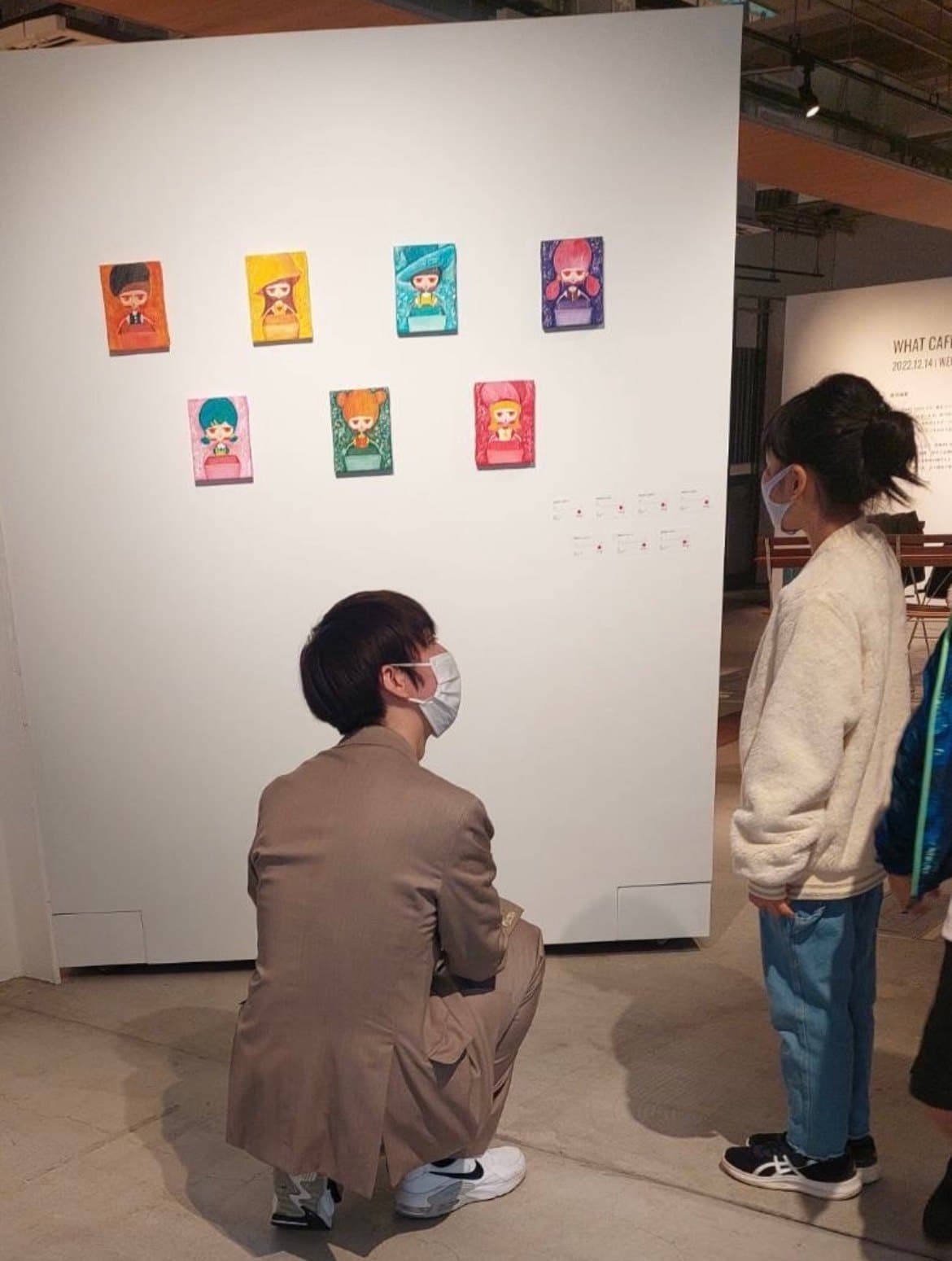 壁に並ぶ小品を見る来場者