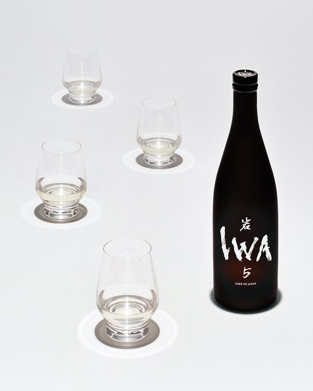 黒いボトルのIWA 5と、酒を注いだ4つのグラス