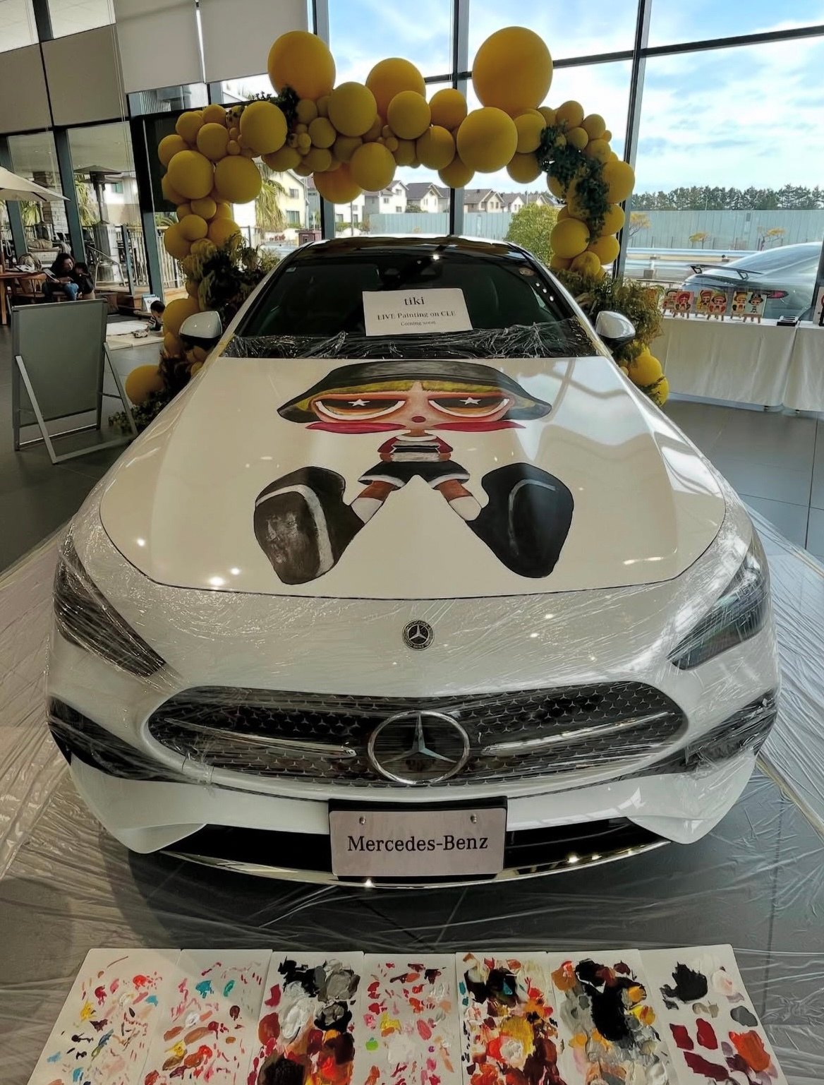 Mercedes-Benz Urayasu: the white car whose body tiki painted, with works set out on the floor beside it